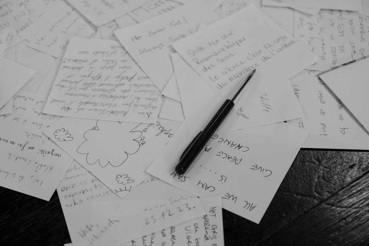 Handwritten note cards and a pen shown in black and white.