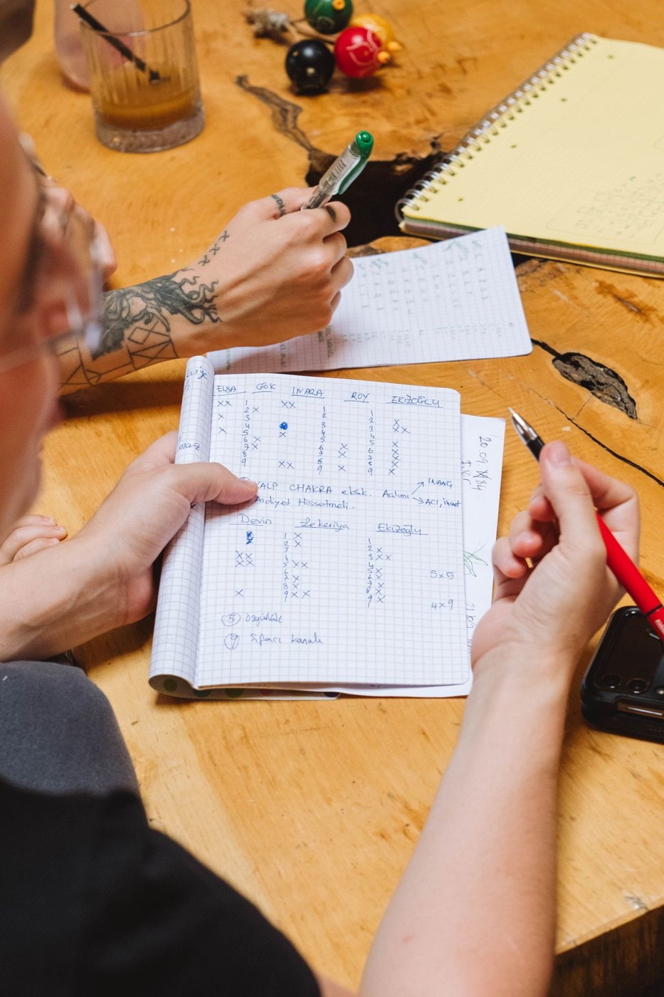 Two people compare handwritten notes across open notebooks.