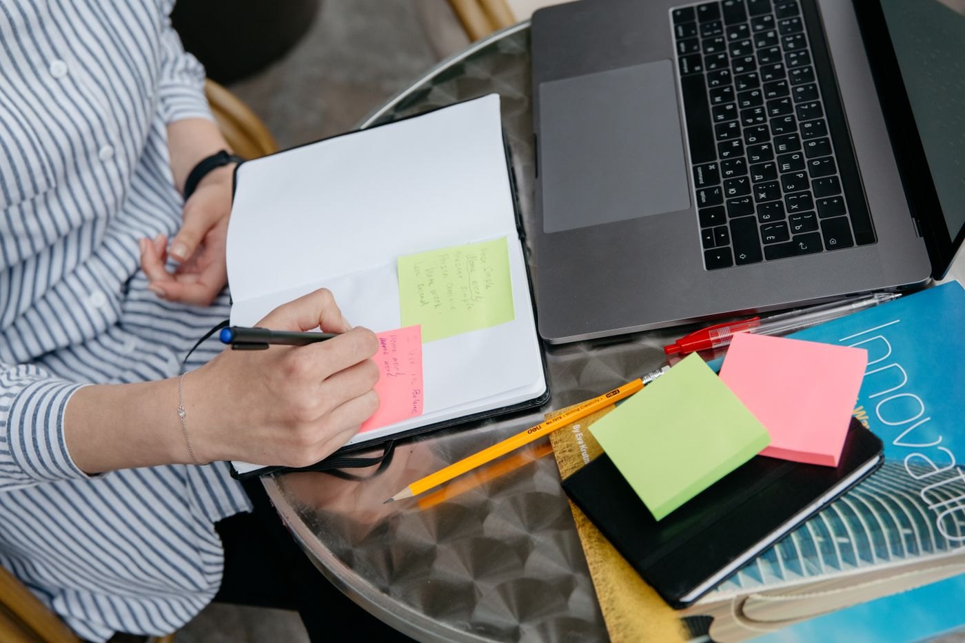 A writer leaves a note beside a laptop and open notebook.