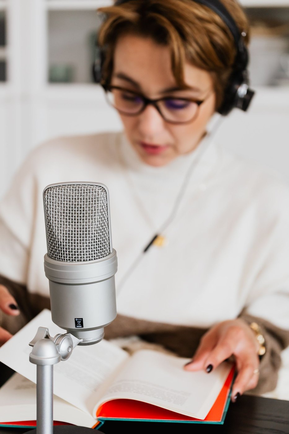 A reader speaks from an open book into a microphone.