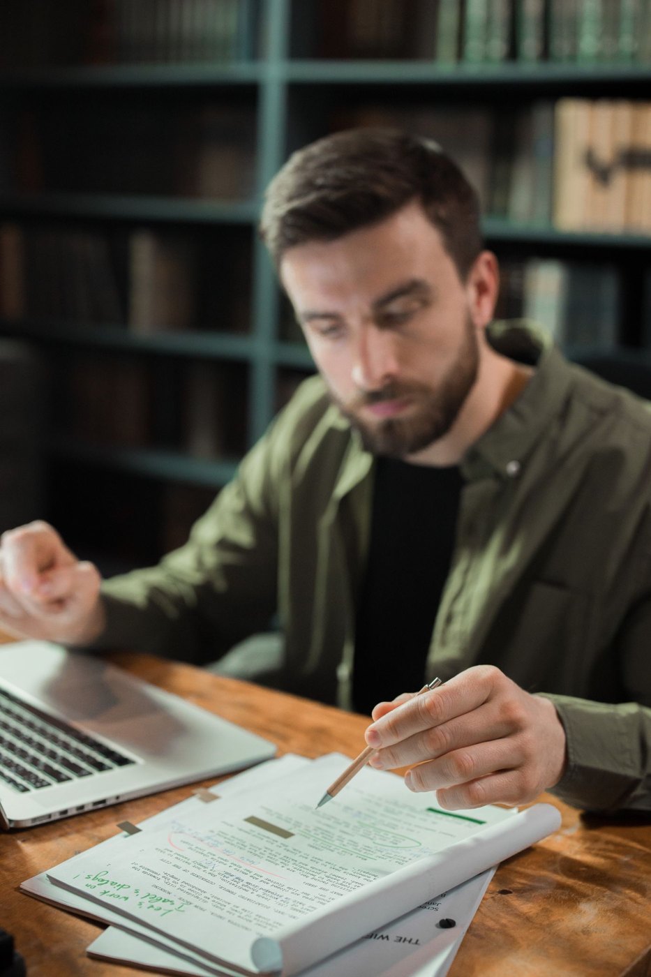 A reader holds a pen while considering notes in a script.