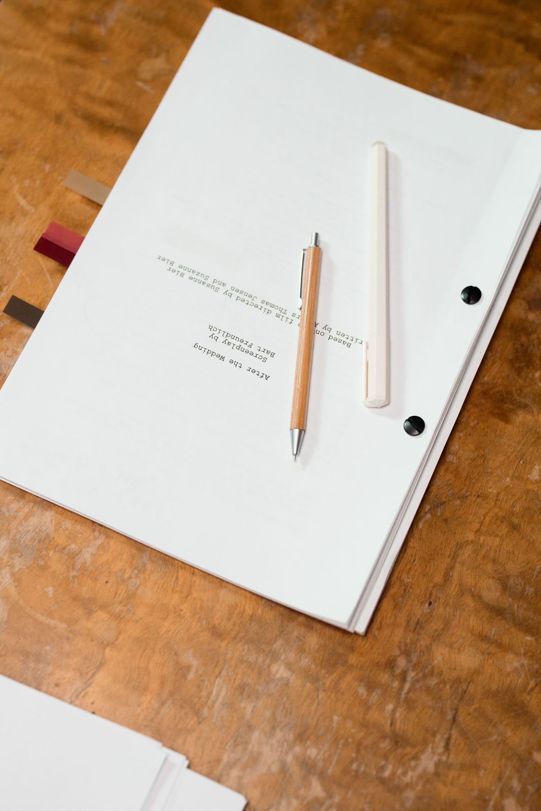 Bound manuscript and pencils resting on a wooden desk
