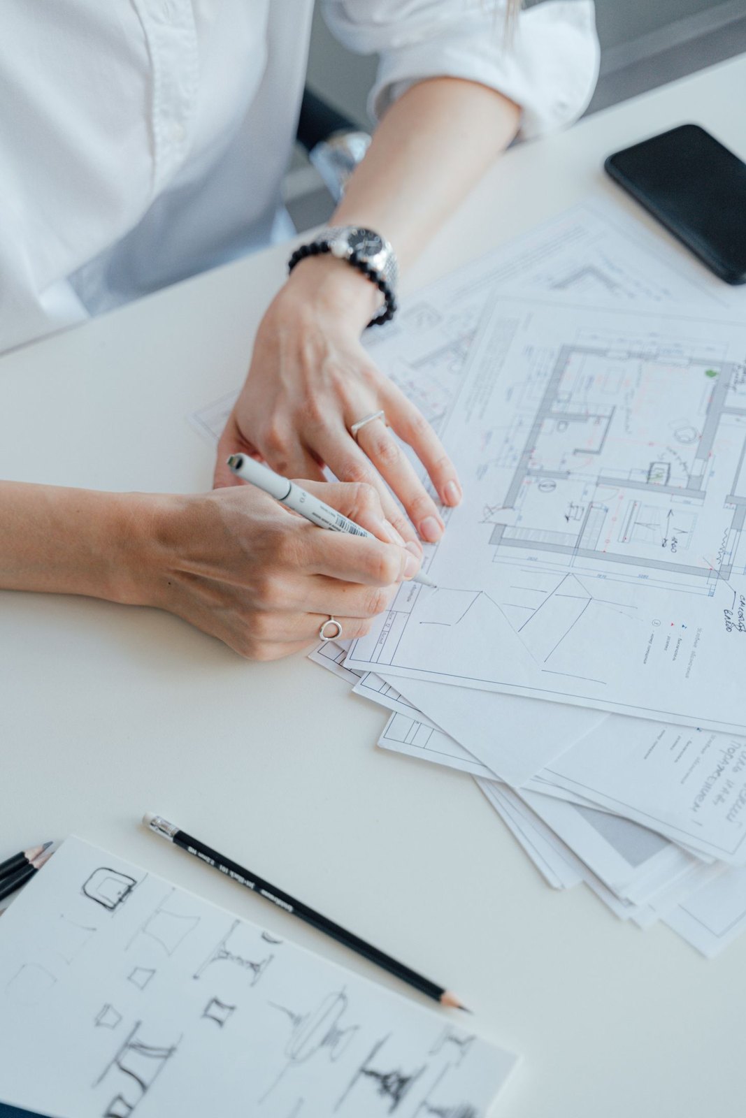 Hands drawing a floor plan with room dimensions