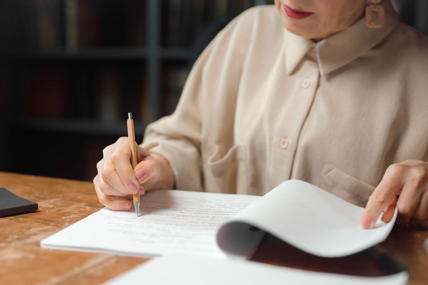 Reader marking a paper manuscript with a pencil