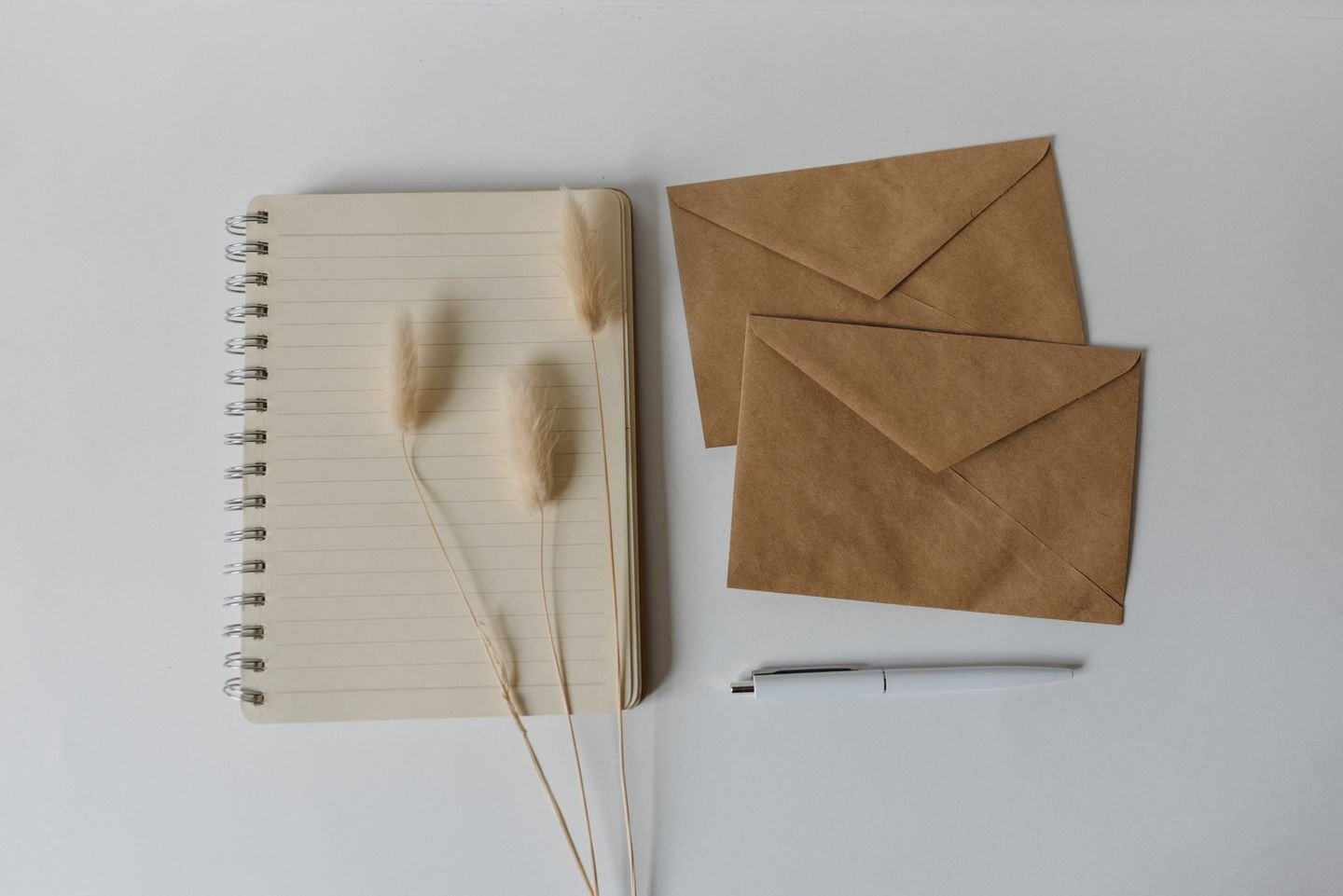 Notebook, envelopes and pen arranged on a wooden surface