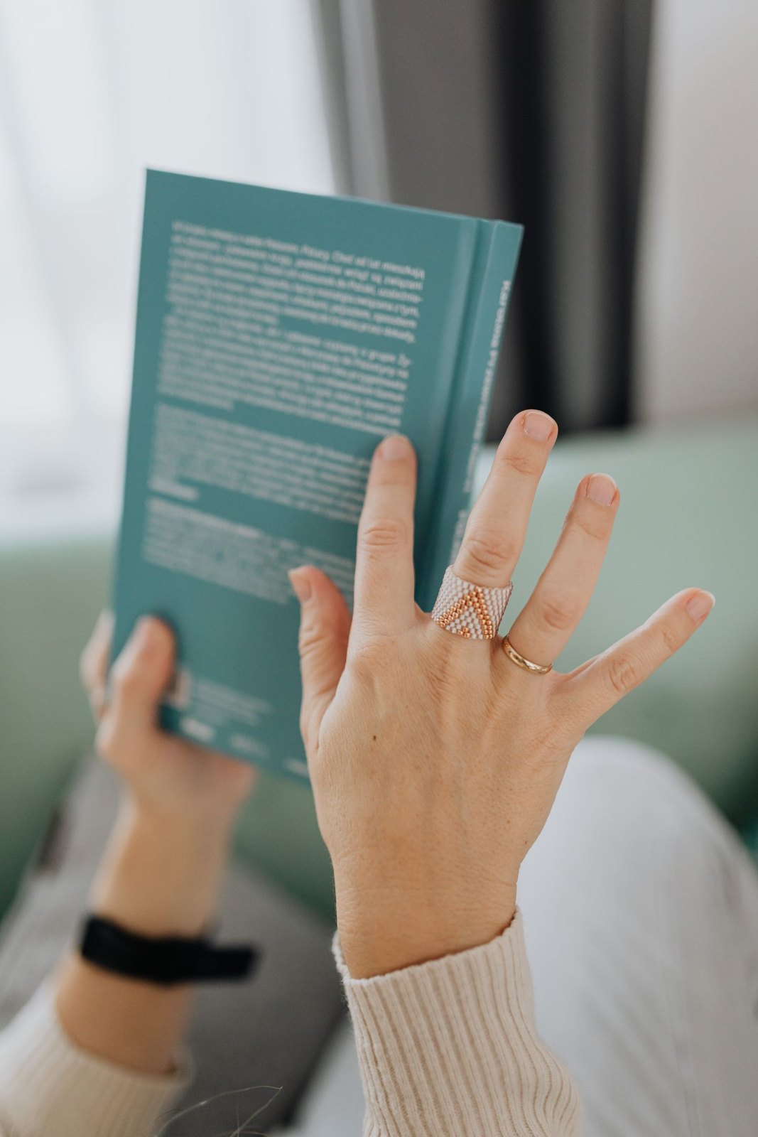 Hands holding a book with its back-cover description visible
