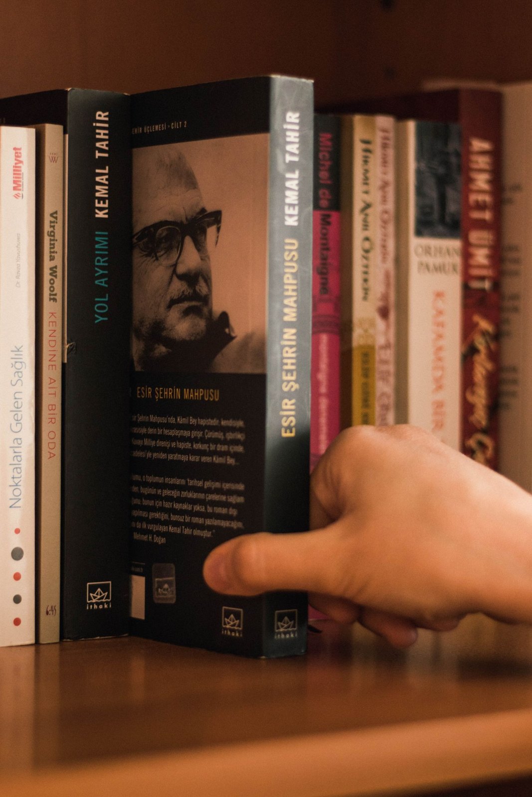 Hand selecting a book with its author portrait and back-cover text visible