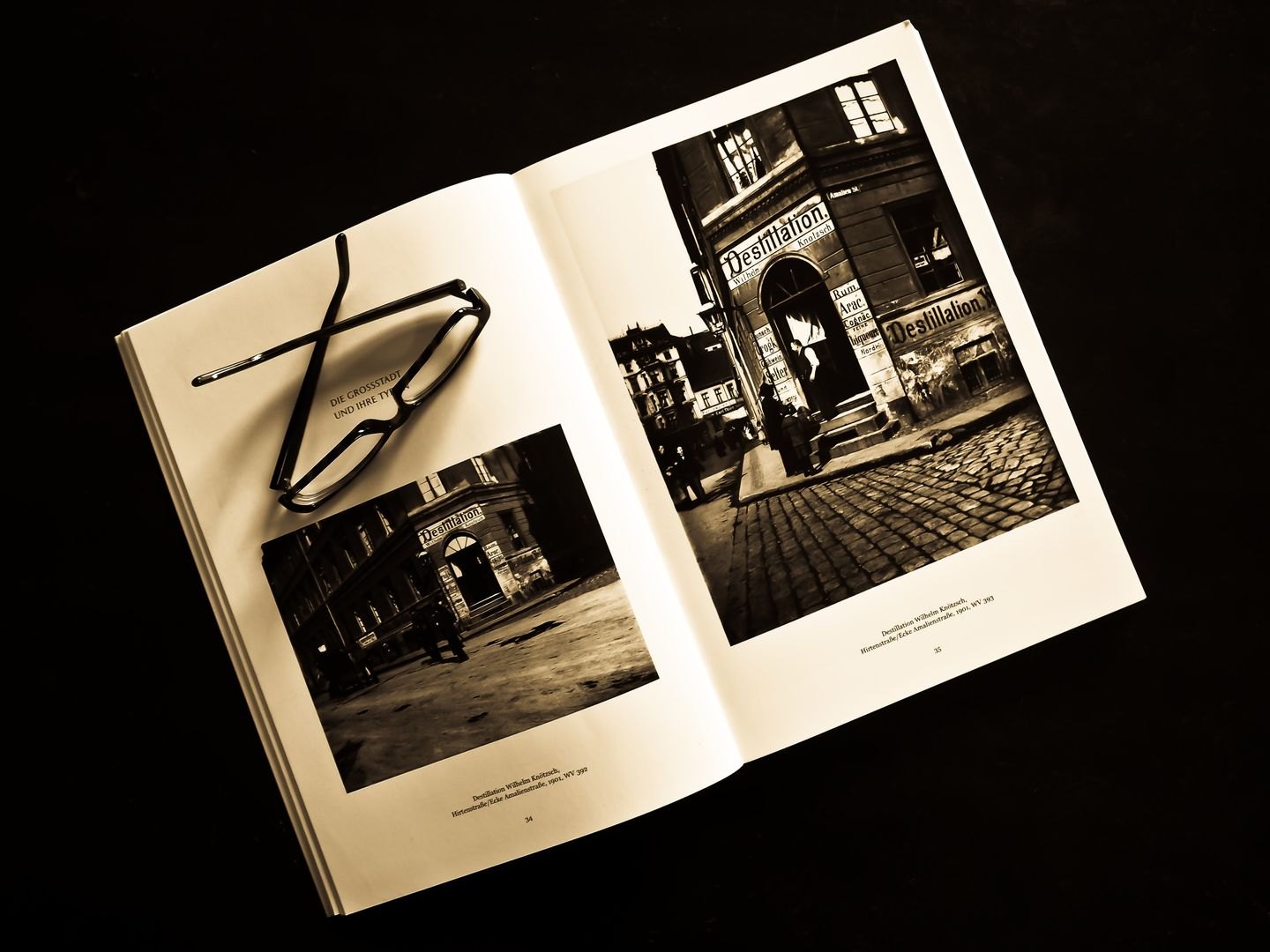 Black-and-white photographs in an open photo book with eyeglasses.