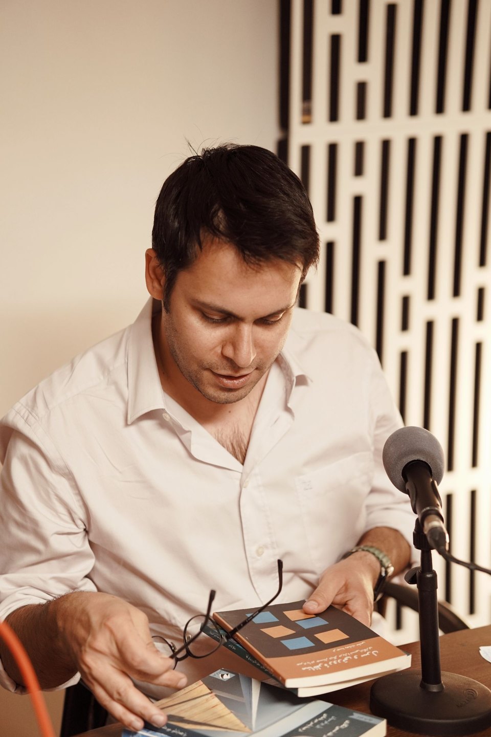 A man holding a book beside a studio microphone.